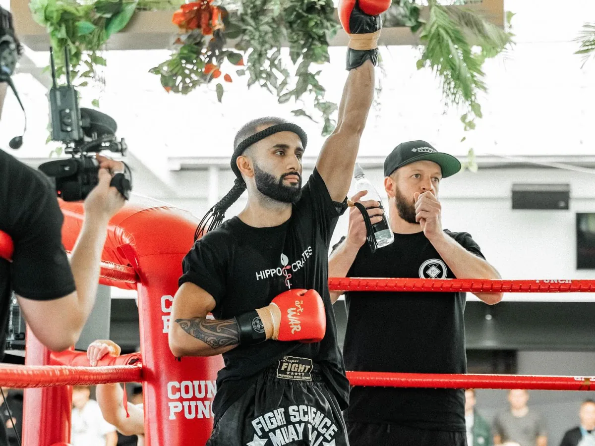 Anurag Thapali standing in the ring with his glove raised after a Muay Thai bout